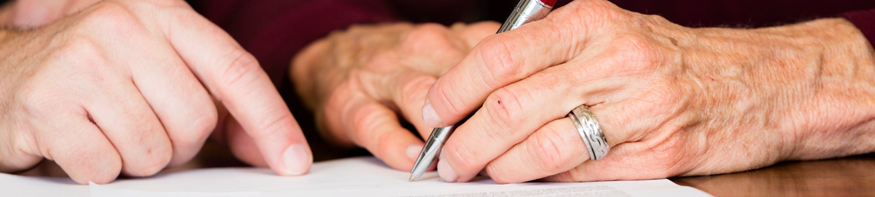 Senior signing a document with a pen