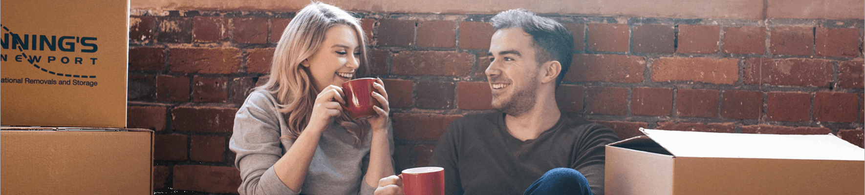 Couple sitting on wooden floor, drinking coffee, moving boxes